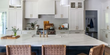 A remodeled luxury kitchen in Atlanta with an island-centric layout, white cabinets, and marble countertops. 