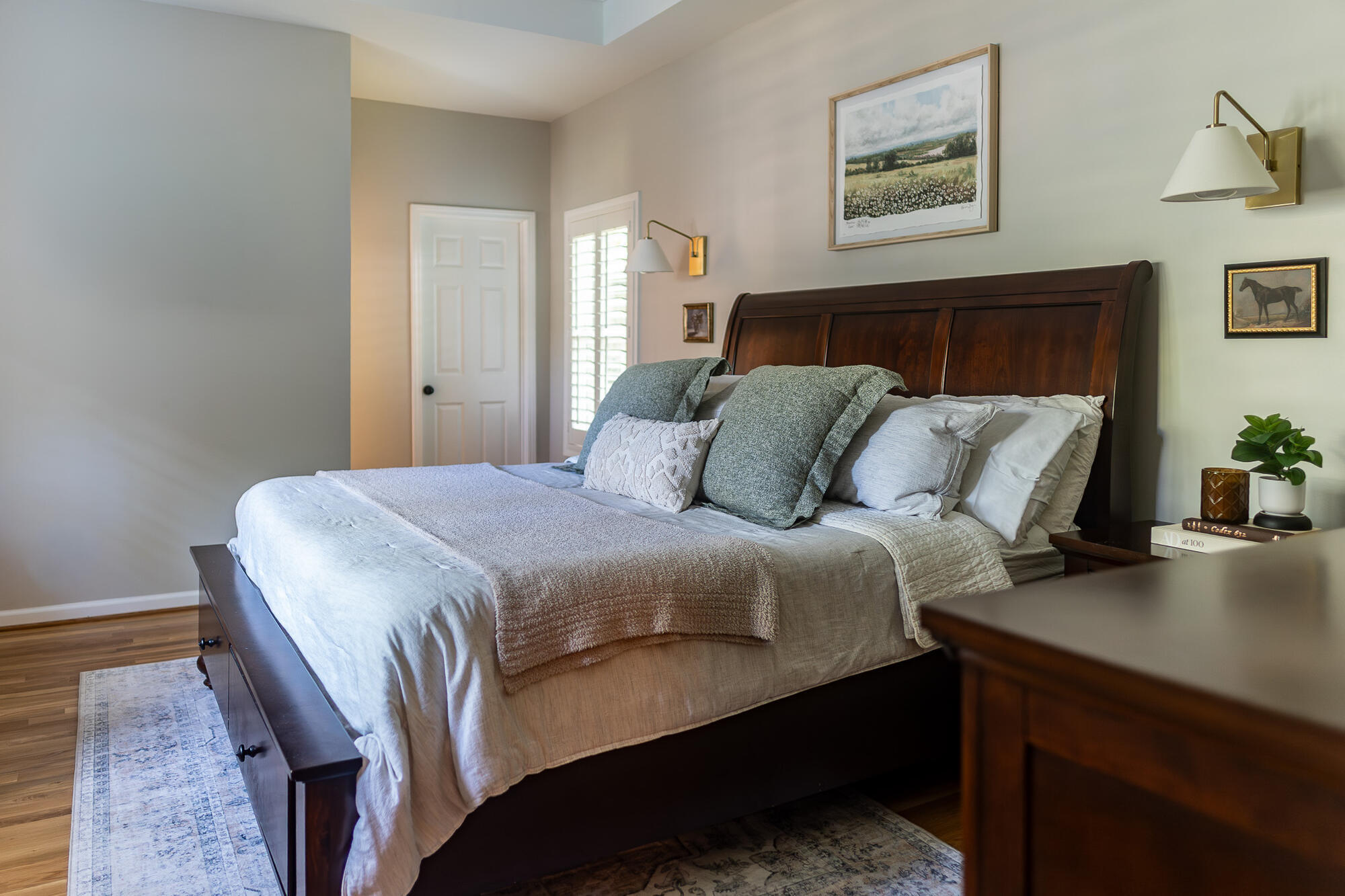 Cozy primary bedroom remodel with wood furniture and modern lighting in Suwanee, GA by Exodus Design Build.