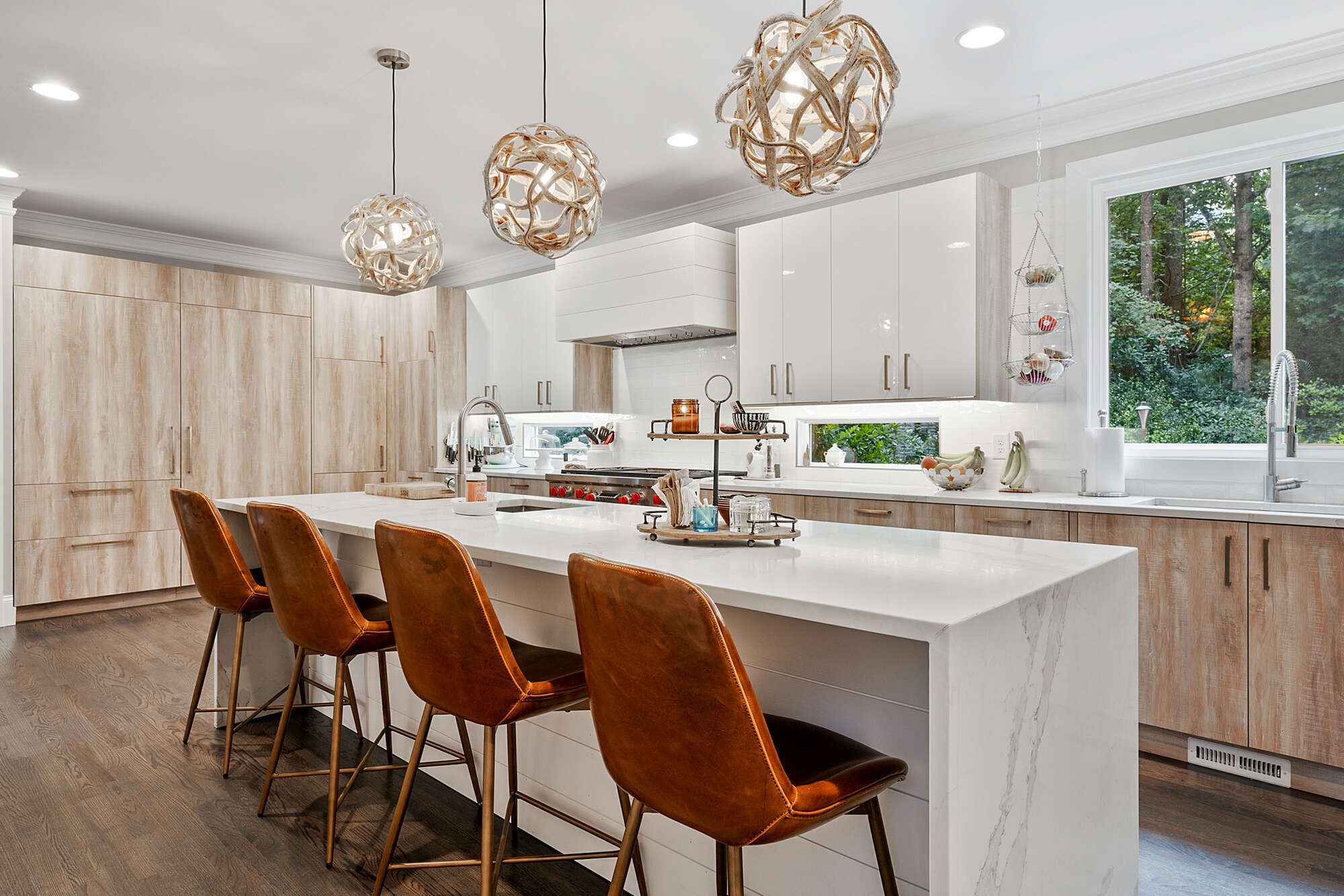 Modern kitchen with white quartz island and leather bar stools in a Johns Creek, GA home by Exodus Design Build.