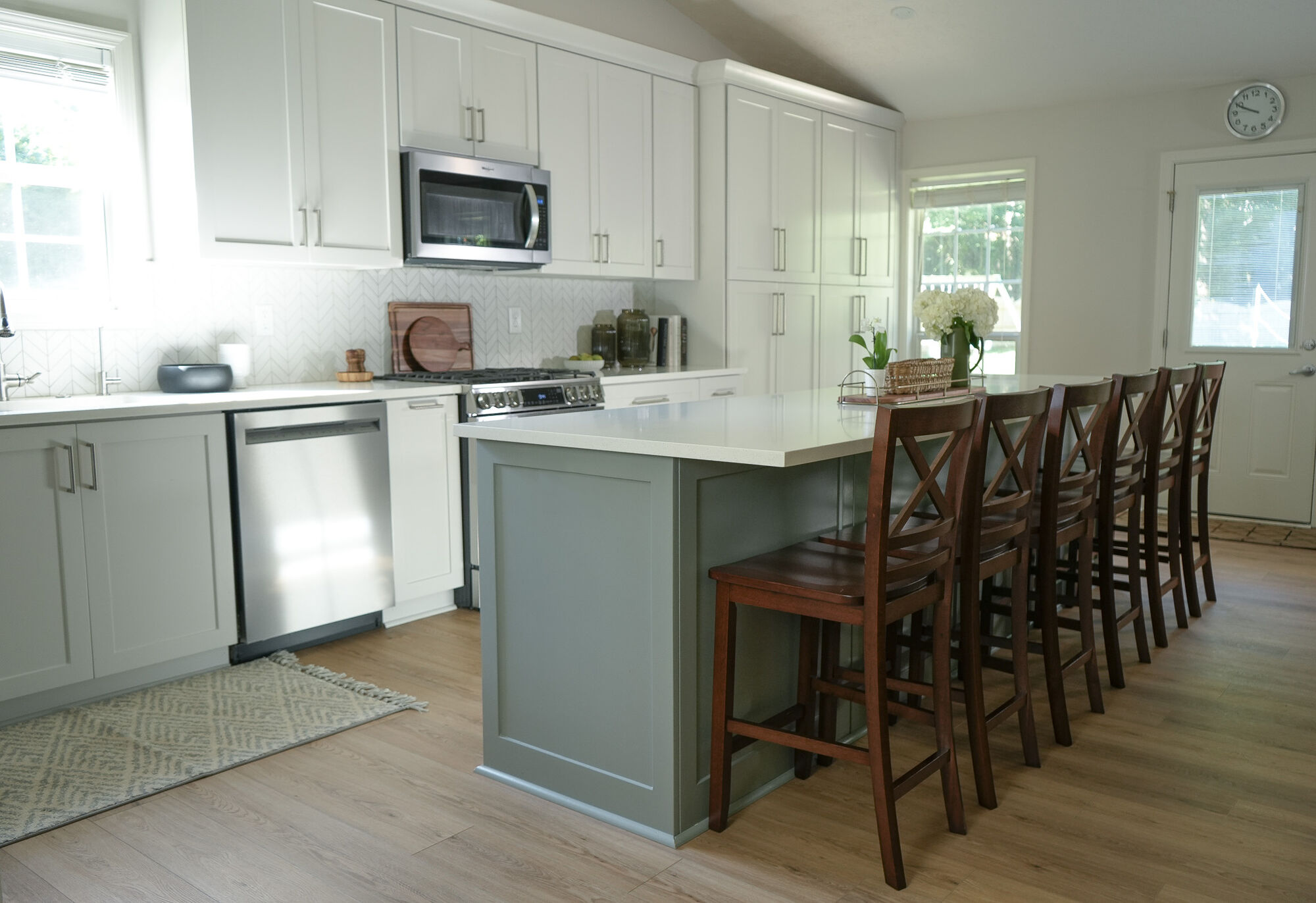 Spacious kitchen with white cabinetry and green island in a custom home by Exodus Design Build in Flowery Branch, GA.