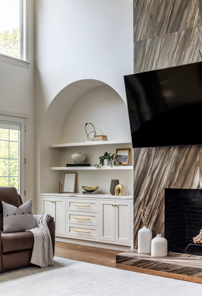 Living room corner with built-in arched shelving and TV wall by Exodus Design Build in Lilburn, GA.