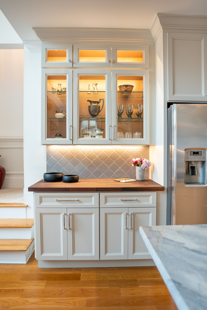 Built-in kitchen display cabinet with glass doors and warm interior lighting by Exodus Design Build in Dacula, GA