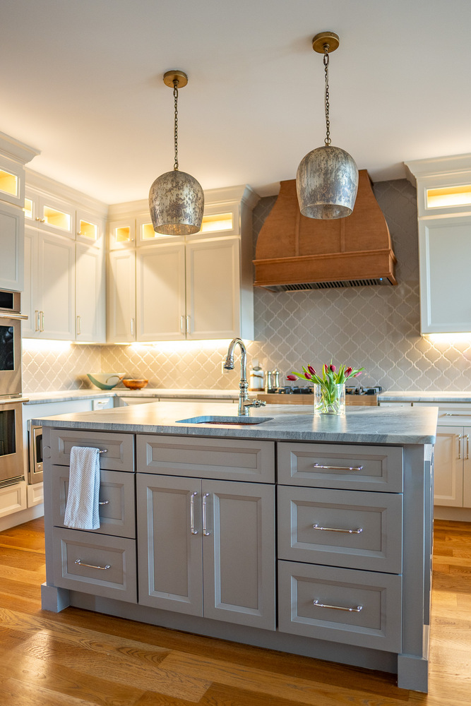Central kitchen island with farmhouse sink and bronze pendant lighting by Exodus Design Build in Sugar Hill, GA