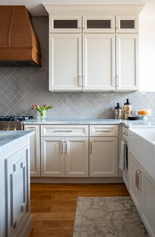 Close-up of custom kitchen wall with soft gray cabinets and wood hood vent by Exodus Design Build in Grayson, GA