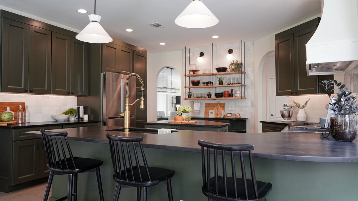Full kitchen view with brass faucet and black bar stools in an Auburn, GA custom home by Exodus Design Build.