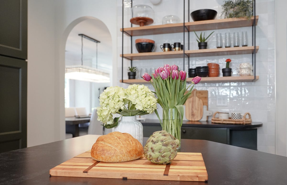 Kitchen island with bread, artichoke, and fresh flowers in a custom home by Exodus Design Build in Suwanee, GA.