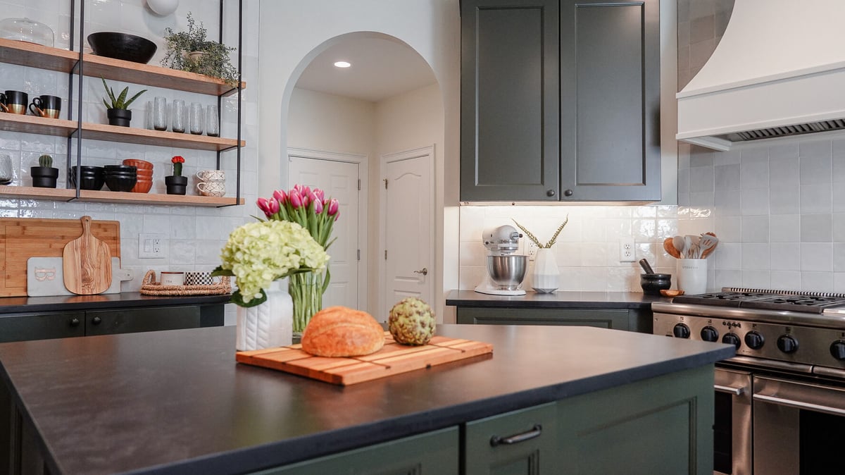 Kitchen island with olive green cabinetry and fresh tulips by Exodus Design Build in Sugar Hill, GA.