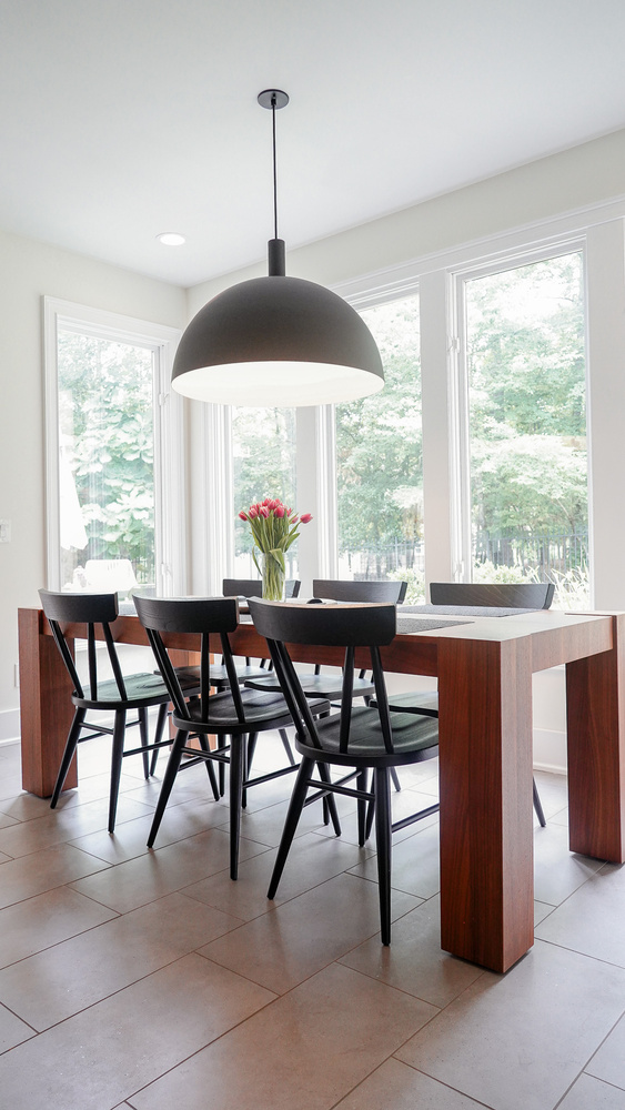 Sleek wooden dining table set against large windows in this Norcross, GA custom home by Exodus Design Build.
