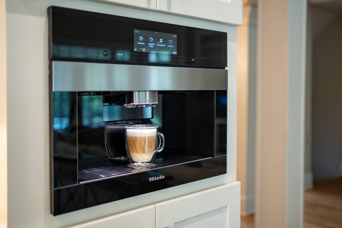 Built-in Miele coffee machine brewing espresso in a high-end kitchen by Exodus Design Build in Duluth, GA.