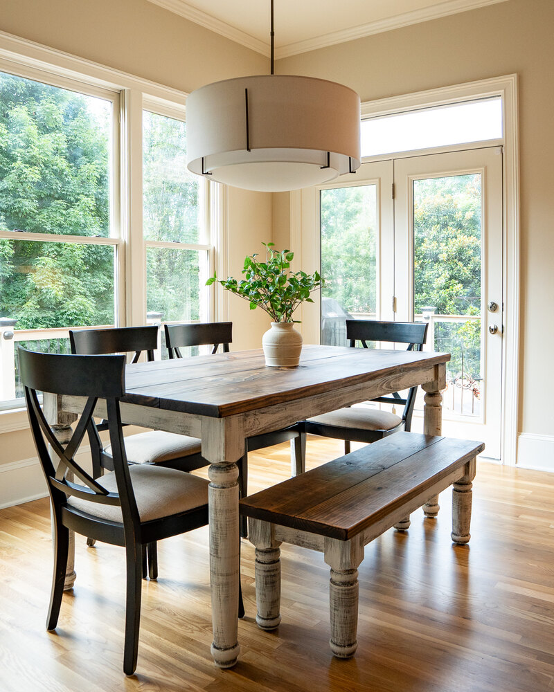 Farmhouse-style dining area with wood furniture and large windows by Exodus Design Build in Buford, GA.
