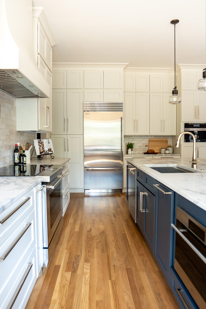 Galley view of custom kitchen with blue island and stainless refrigerator by Exodus Design Build in Georgia.