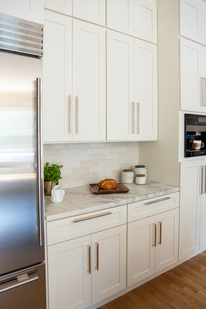 Kitchen counter with marble surface and upper cabinetry by Exodus Design Build in Suwanee, GA