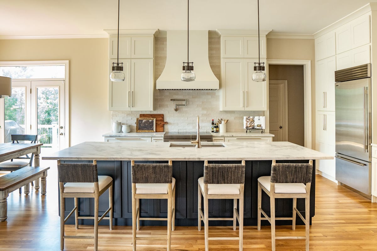 Marble kitchen island with white cabinetry and pendant lighting in a Gainesville, GA custom home by Exodus Design Build.