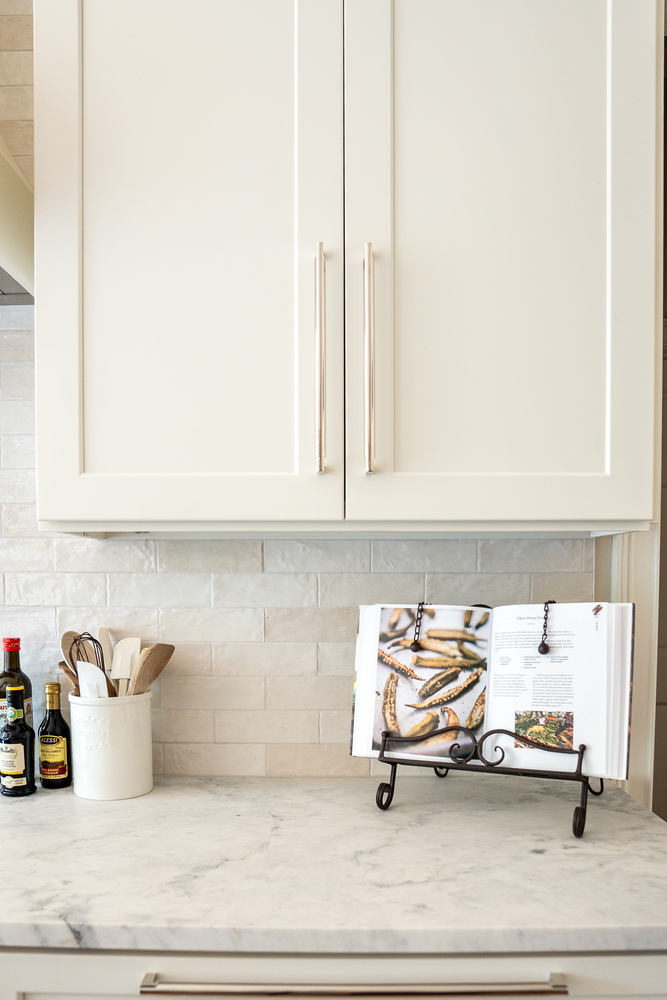Recipe book stand and cooking essentials on marble counter in custom kitchen by Exodus Design Build in Braselton, GA