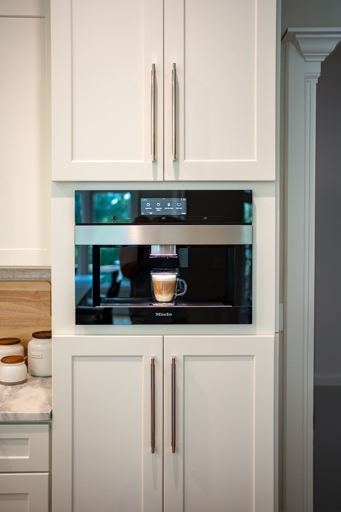 Sleek white cabinet kitchen with built-in espresso machine by Exodus Design Build in Stone Mountain, GA.
