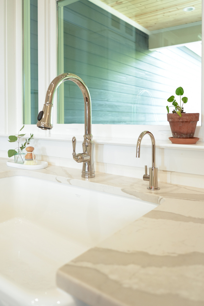 Detailed chrome kitchen faucet with quartz counters and houseplants by Exodus Design Build in Gainesville, GA