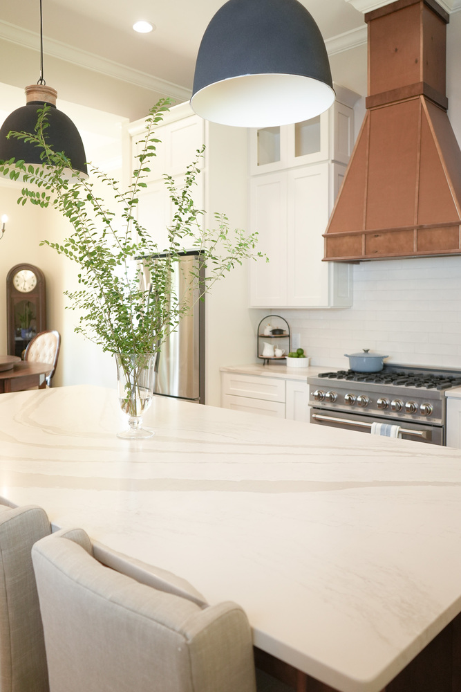 Oversized kitchen island with veined countertop and soft neutral chairs by Exodus Design Build in Snellville, GA