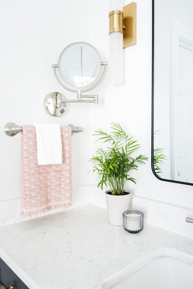 Bathroom counter with lighted mirror and gold accents by Exodus Design Build in Johns Creek, GA.