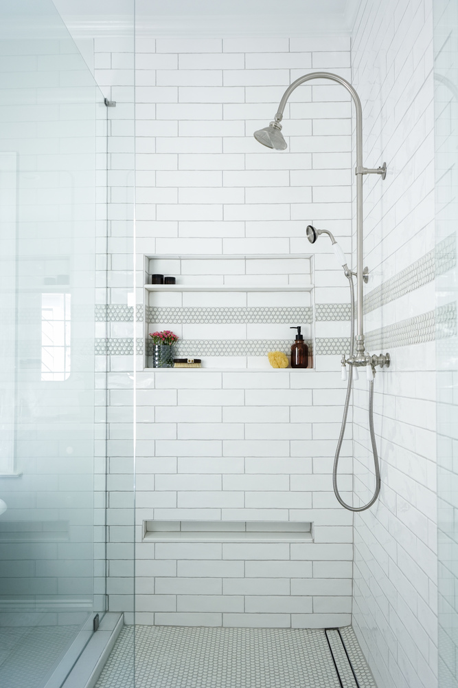 Minimalist walk-in shower with rainfall head and niche shelving by Exodus Design Build in Flowery Branch, GA.