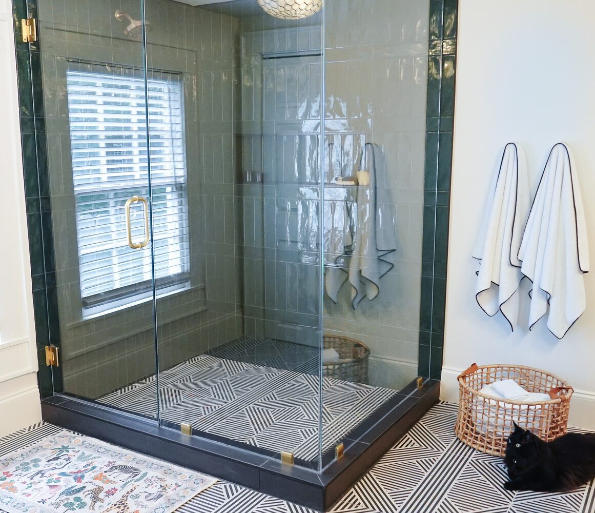 Bathroom with vertical green tile, white trim, and cozy bath accessories by Exodus Design Build in Loganville, GA.