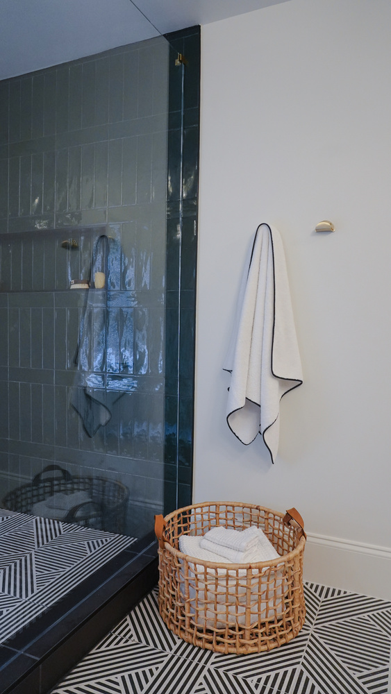 Custom shower entry with white towel and woven basket designed by Exodus Design Build in Sugar Hill, GA.