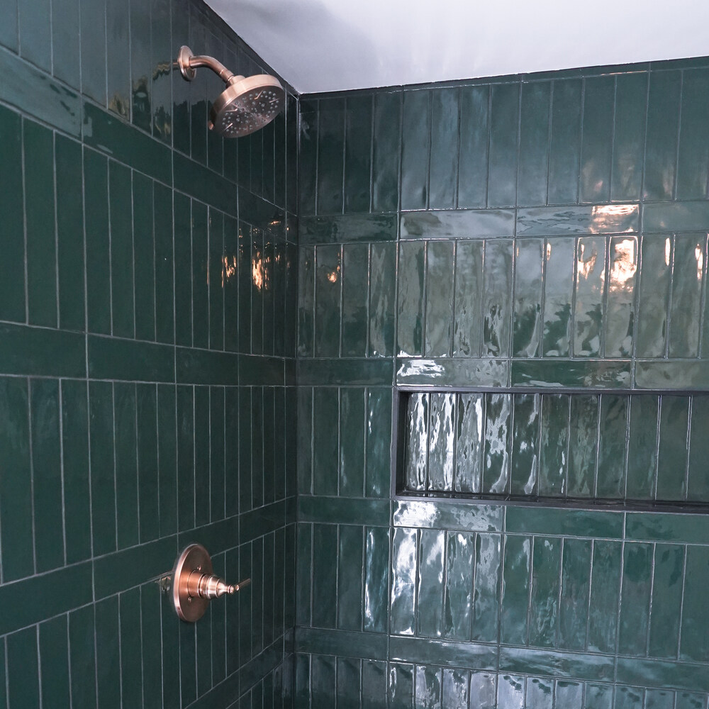 Custom shower featuring emerald green tiles and brass fixtures by Exodus Design Build in Johns Creek, GA.