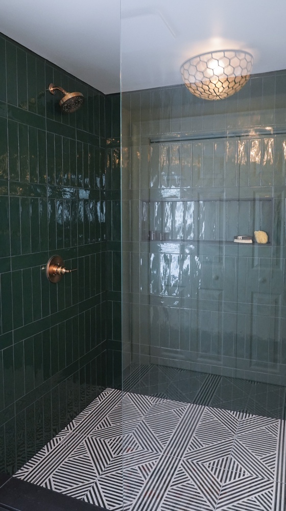 Custom walk-in shower with dual tone green tiles and decorative ceiling light by Exodus Design Build in Georgia.