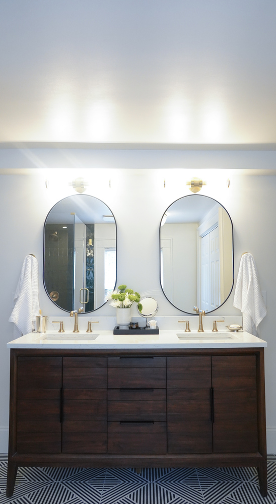 Double vanity with black-framed mirrors and brass fixtures in a custom home by Exodus Design Build in North Metro, GA.