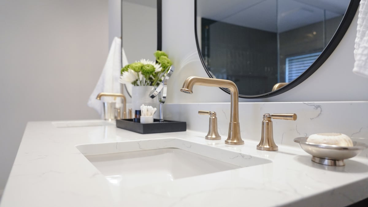 Elegant dual-sink vanity with gold fixtures in a custom home bathroom by Exodus Design Build in Buford, GA.