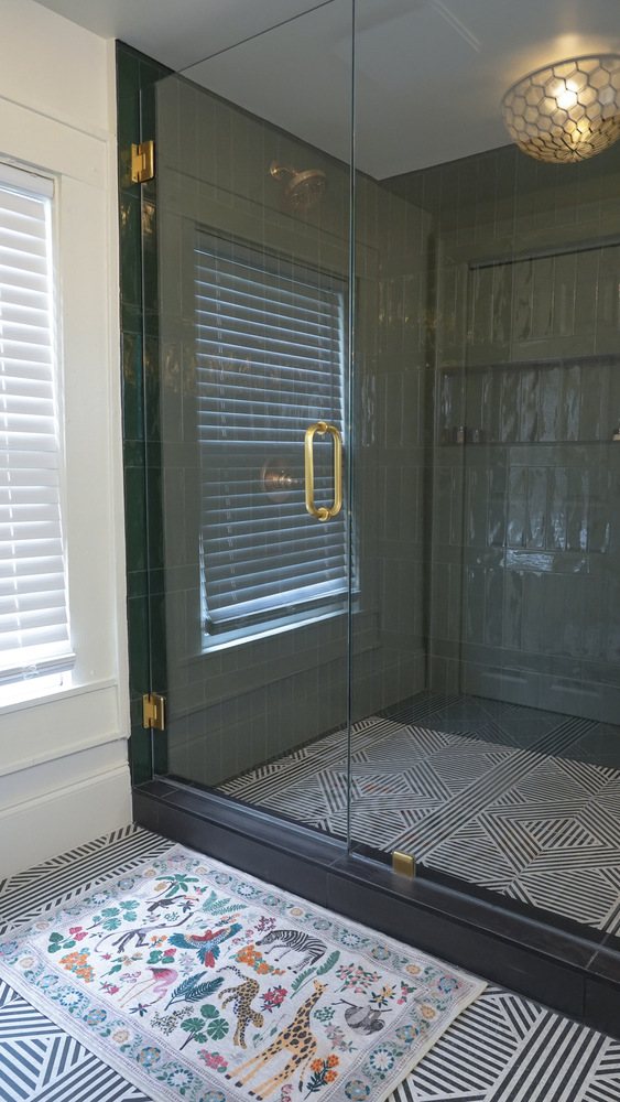 Frameless glass shower with gold hardware and geometric flooring by Exodus Design Build in Snellville, GA.