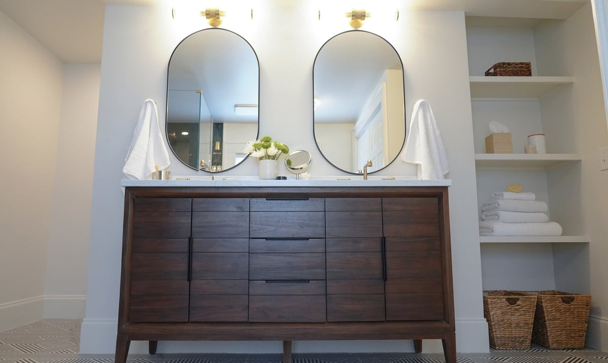 Full vanity view with towel shelving and elegant lighting in a luxury bathroom by Exodus Design Build in Suwanee, GA.