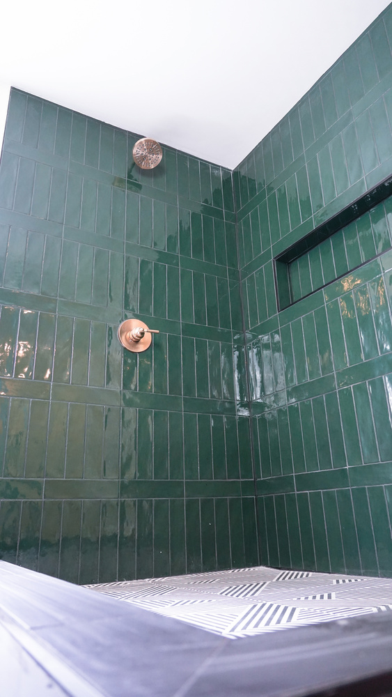 Green tile shower corner with recessed shelf in a custom home by Exodus Design Build in Oakwood, GA.