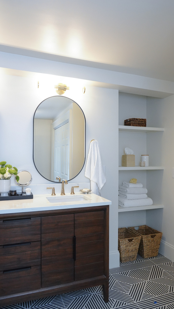 Modern bathroom with stacked towels and open storage shelves by Exodus Design Build in Flowery Branch, GA.