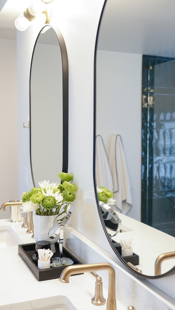 Modern double vanity with black framed mirror and brass fixtures in a custom bathroom by Exodus Design Build in Duluth, GA.