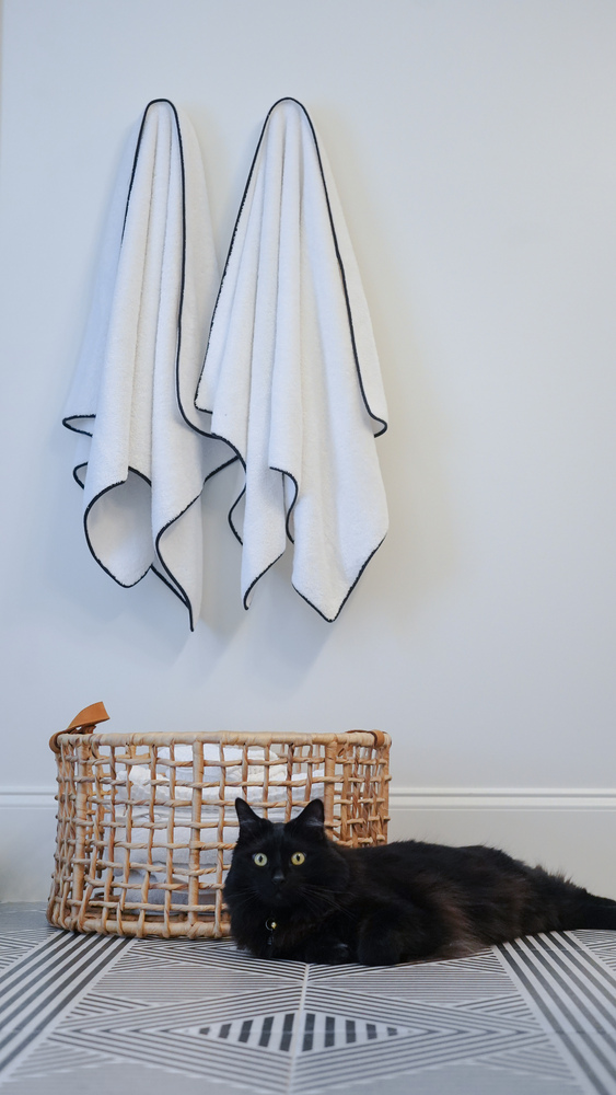 Wicker towel basket and twin white towels with black trim in a custom home by Exodus Design Build in Peachtree Corners, GA.