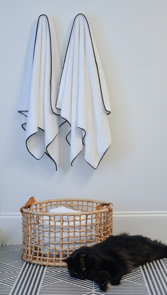 Wicker towel basket with folded linens under dual hanging towels by Exodus Design Build in Redan, GA.