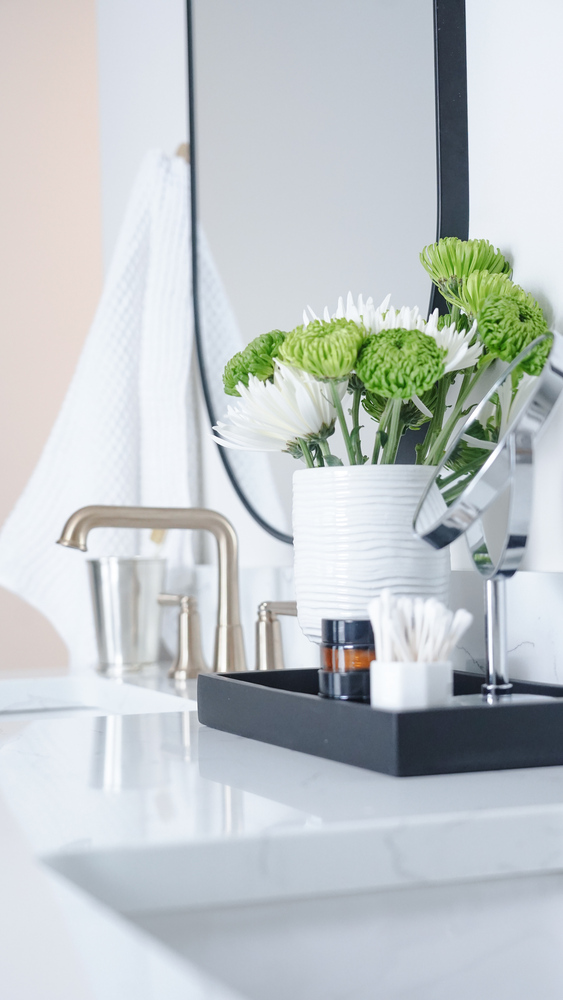 anity close-up with white and green florals and brass fixtures in a custom bath by Exodus Design Build in Stone Mountain, GA.