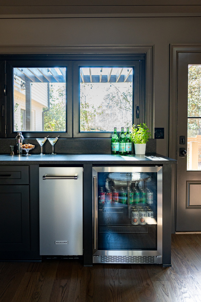 Built-in beverage center with glass door fridge and dark countertops by Exodus Design Build in Norcross, GA