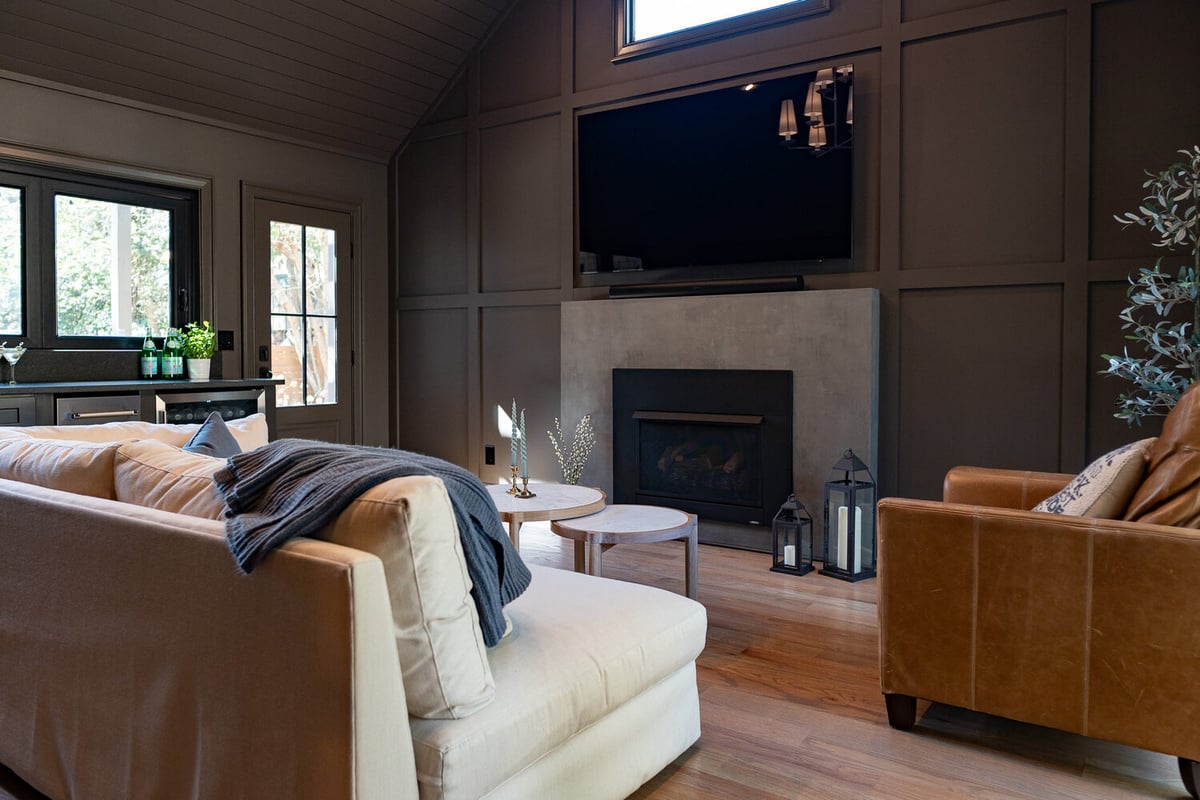 Cozy living room with fireplace, tall ceilings, and bar access by Exodus Design Build in North Metro, GA