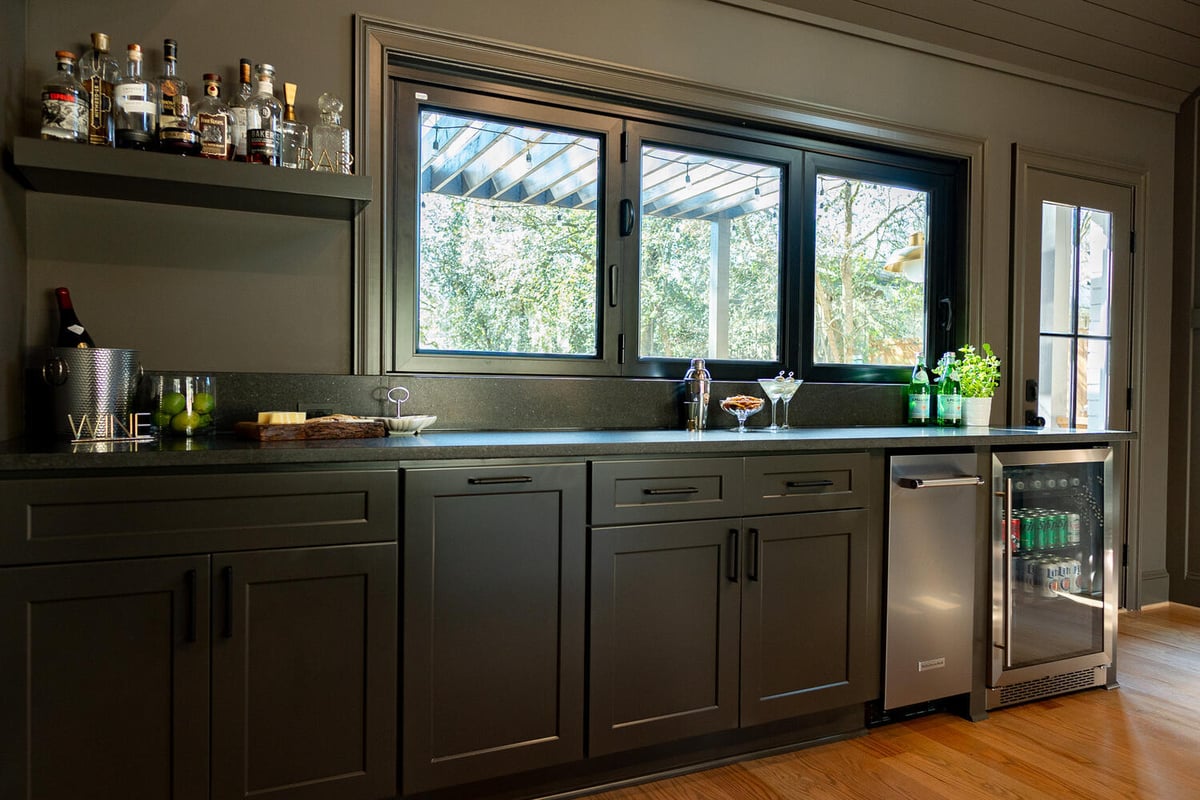 Custom home indoor bar with dark cabinetry and beverage fridge by Exodus Design Build in Lawrenceville, GA