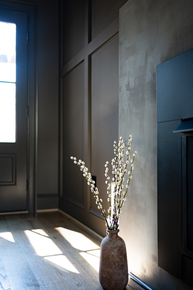 Decorative vase with pussy willow branches beside fireplace in soft daylight by Exodus Design Build in Grayson, GA