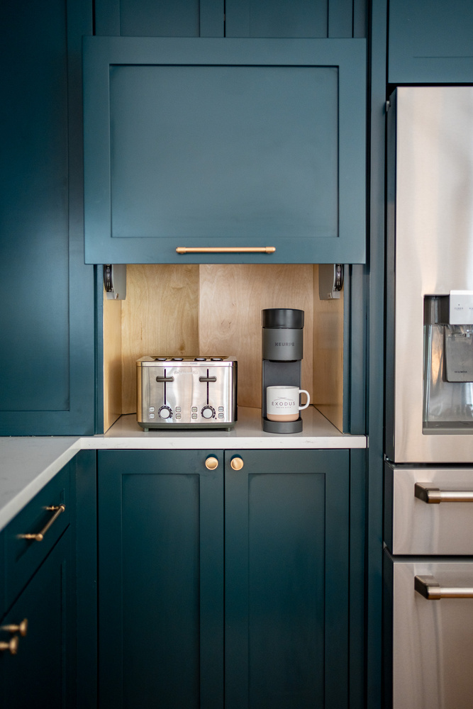 Hidden kitchen station with Keurig machine and branded mug in custom home by Exodus Design Build in Auburn, GA