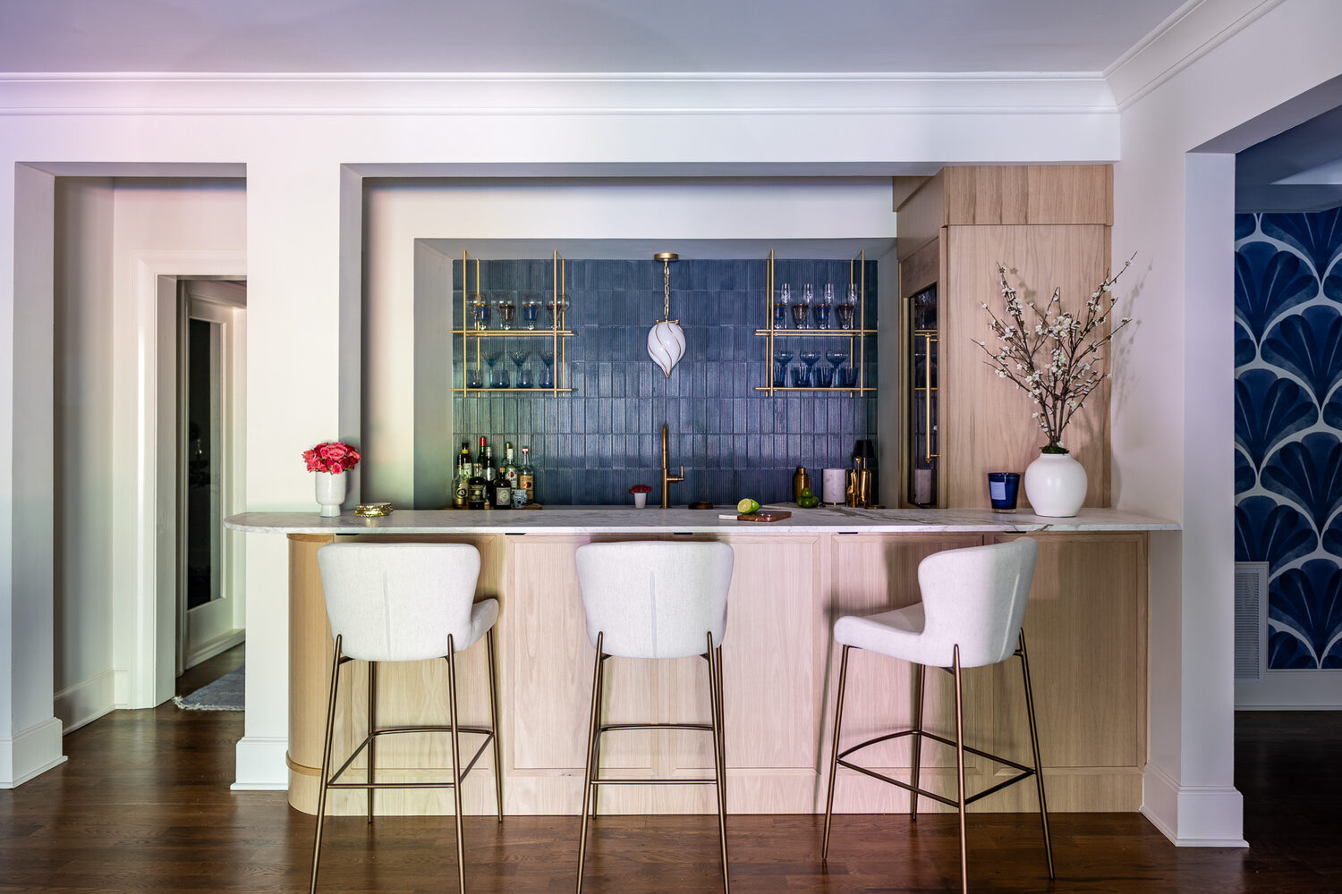 Elegant in-home bar setup with tall stools and wood cabinetry by Exodus Design Build in Sugar Hill, GA.