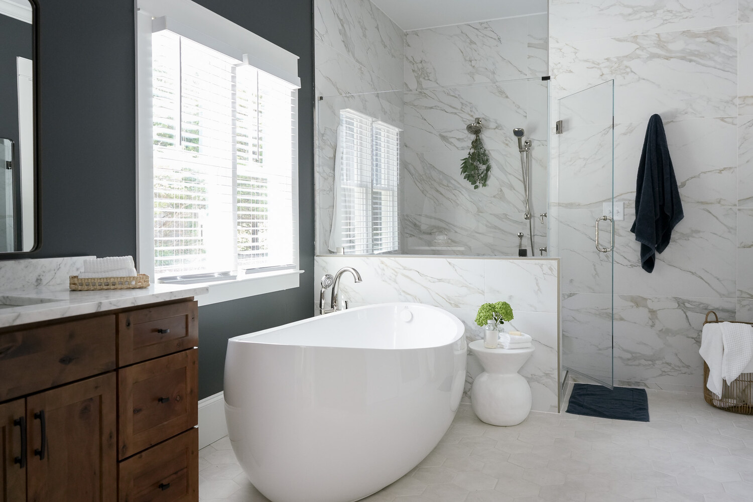 Elegant white freestanding bathtub in a marble-clad bathroom renovation in Atlanta, GA by Exodus Design Build