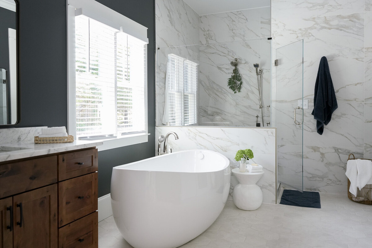Elegant white freestanding bathtub in a marble-clad bathroom renovation in Atlanta, GA by Exodus Design Build