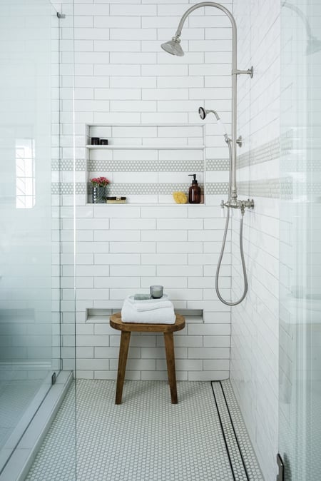 Custom tiled shower with bench and wood accent stool in Atlanta bathroom by Exodus Design Build