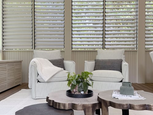 Cozy screened-in porch with neutral armchairs and modern window louvers by Exodus Design Build in Decatur, GA.