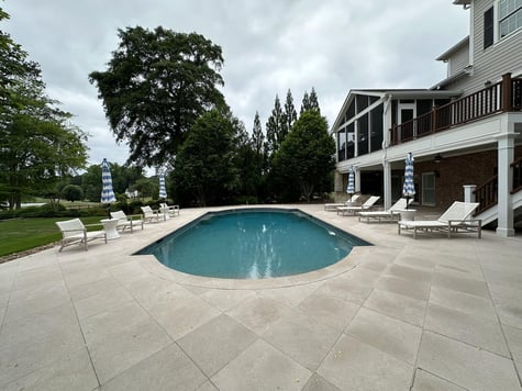 Custom outdoor living space with expansive pool and elevated porch by Exodus Design Build in Oakwood, GA.