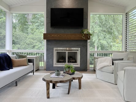 Full view of a custom screened-in porch with fireplace, large TV, and modern seating by Exodus Design Build in Auburn, GA.