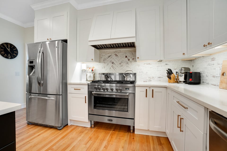 Custom kitchen featuring stainless steel gas range and white brick backsplash by Exodus Design Build in Decatur, GA.